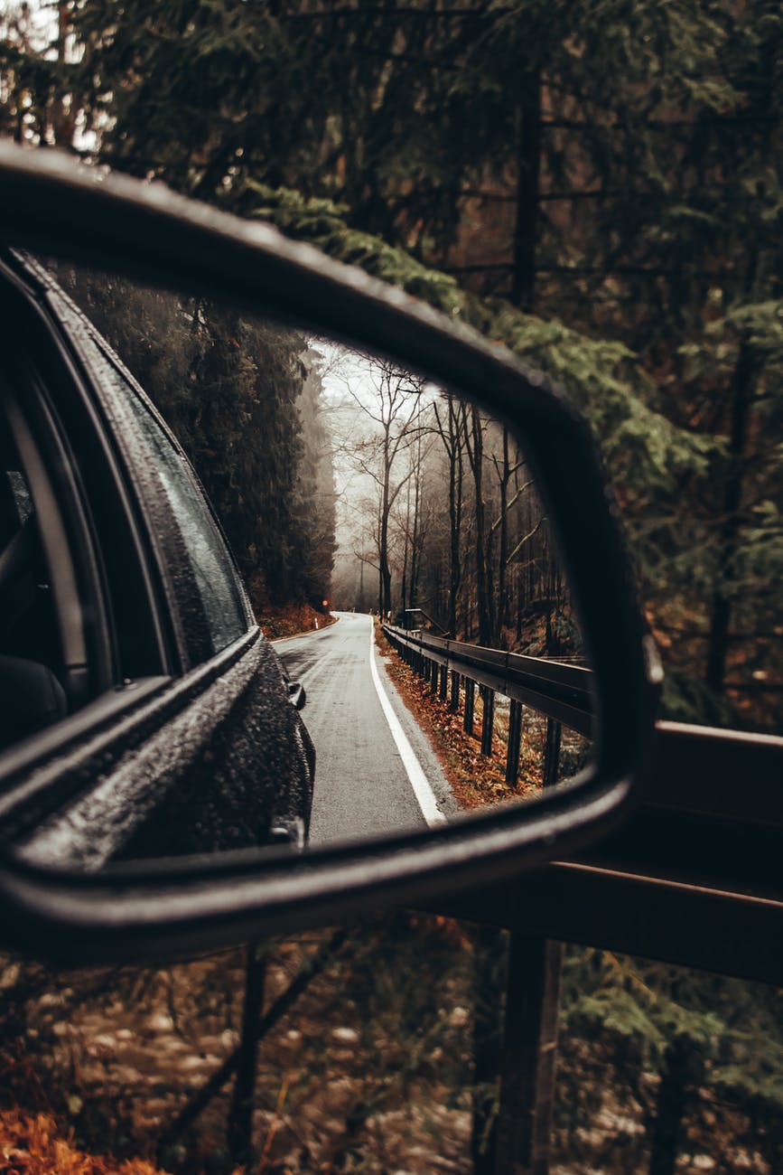 a side mirror with an image of a wet car on the road